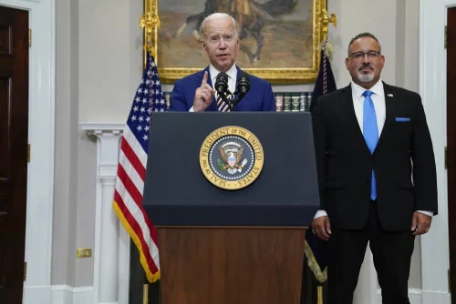 President Joe Biden speaks about student loan debt forgiveness in the Roosevelt Room of the White House, Aug. 24, 2022, in Washington. Education Secretary Miguel Cardona listens at right. (AP Photo/Evan Vucci, file)