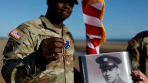 A soldier shows the Distinguished Service Cross while another holds the portrait of of Waverly Woodson Jr., who was part of the only Black combat unit to take part in the D-Day invasion being posthumously awarded the Distinguished Service Cross. (AP Photo/Jeremias Gonzalez)
